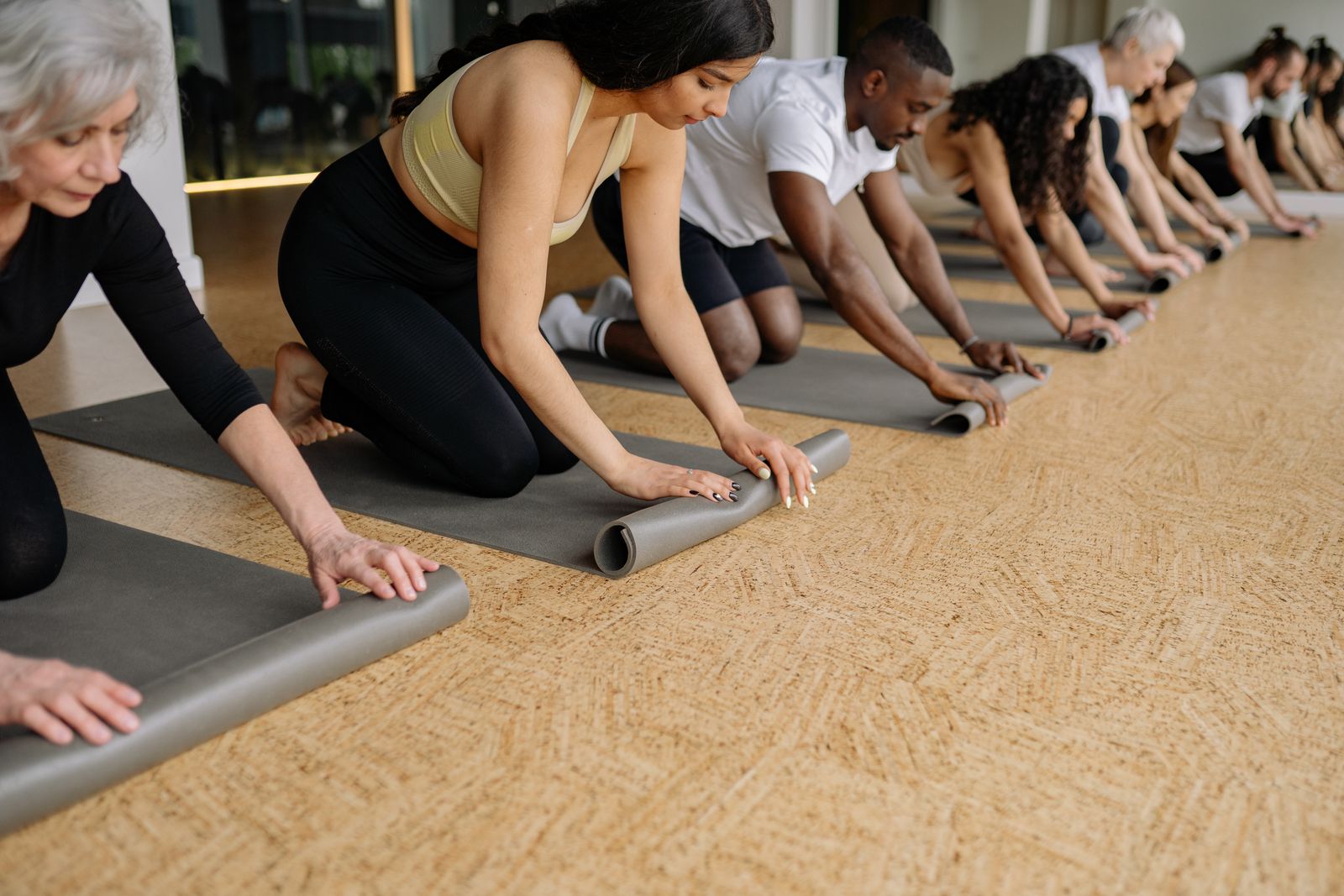 Students kneeling in a row, unrolling their yoga mats
