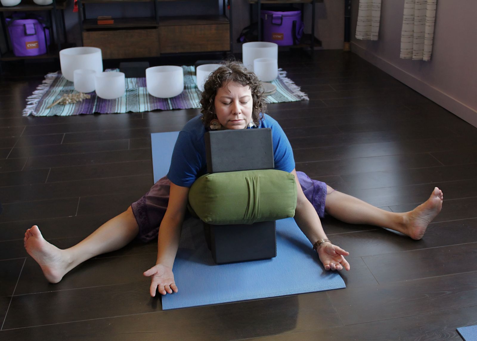 A student resting over a bolster and blocks on a mat